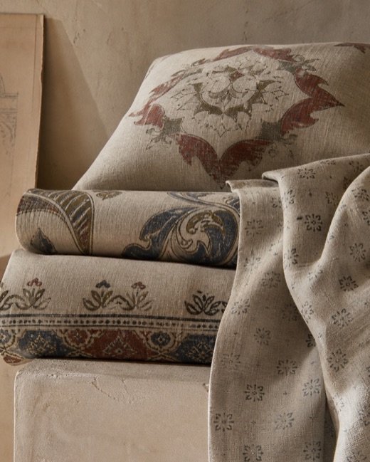 Linen cushions and throw printed with an archival medallion, a paisley border and micro-geometric motifs in faded red, indigo and olive.